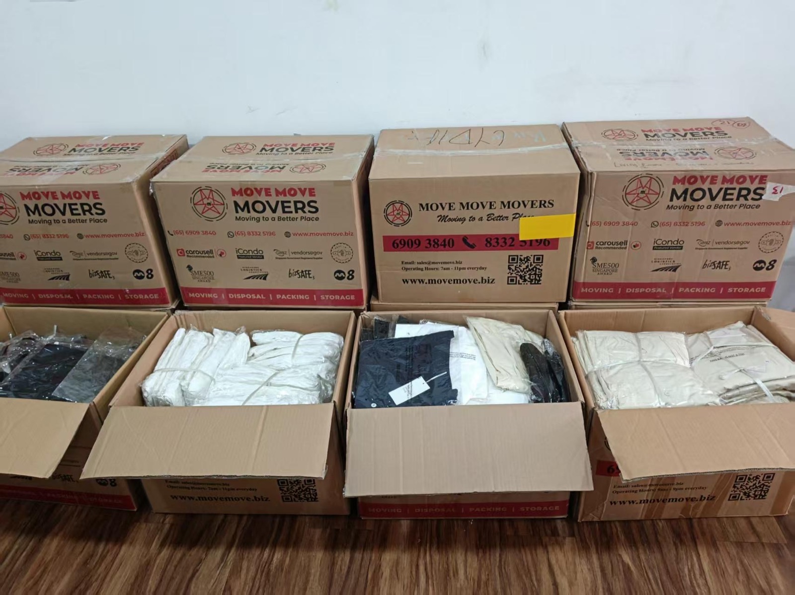 Open Move Move Movers cartons containing packaged white and dark clothing