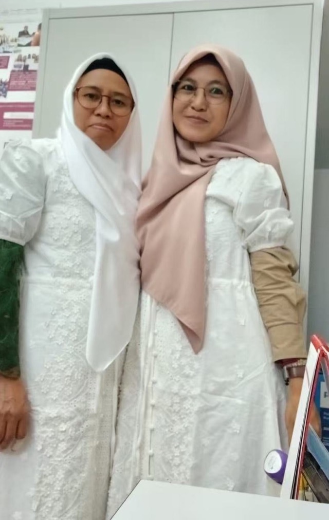 Two adults posing together in white clothing