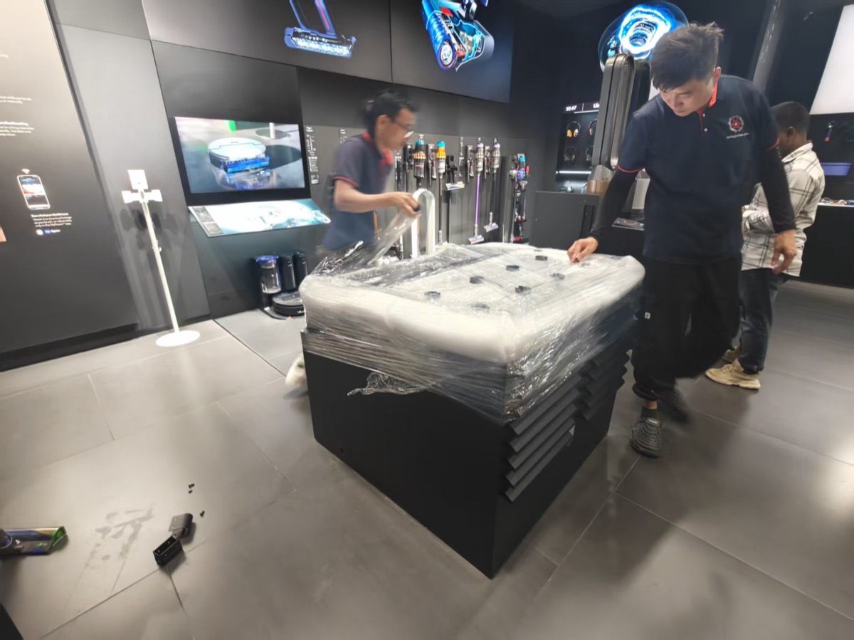 Move Move Movers crew applying protective wrap to a Dyson retail fixture