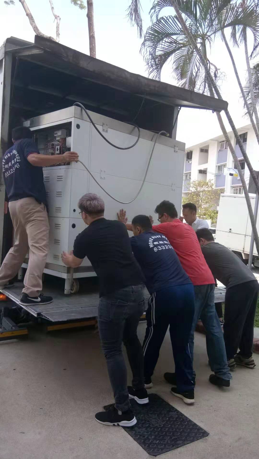 Large commercial cabinet being pushed onto a truck tailgate in Singapore