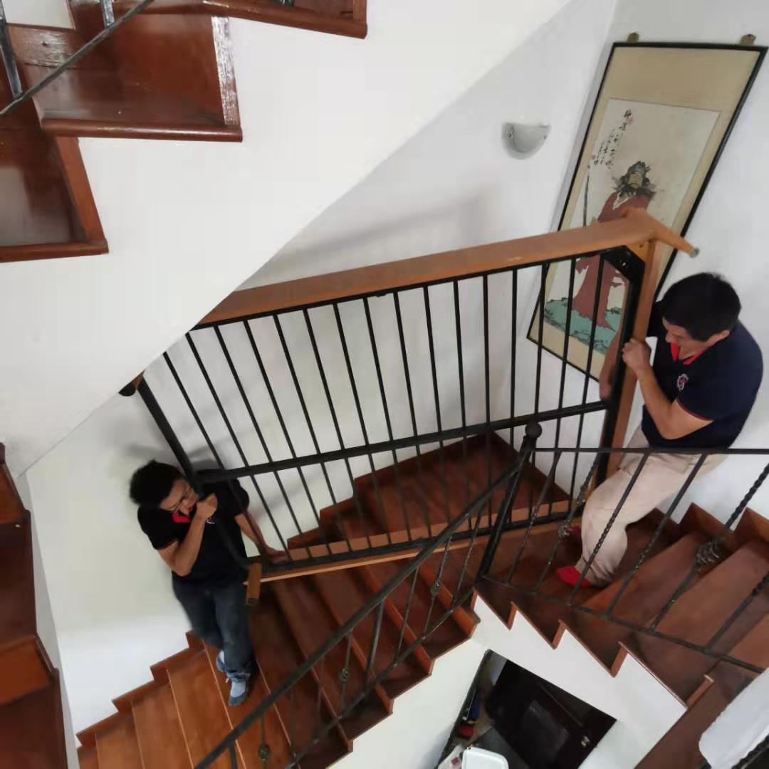 Bed-frame parts being carried down a staircase during a Singapore disposal job