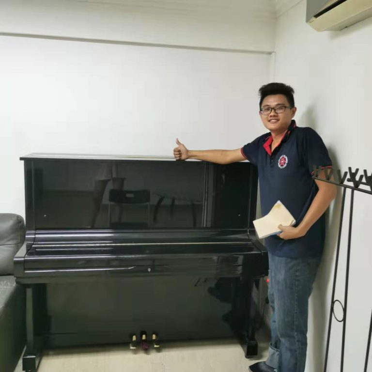 Move Move Movers team member standing beside a black upright piano indoors