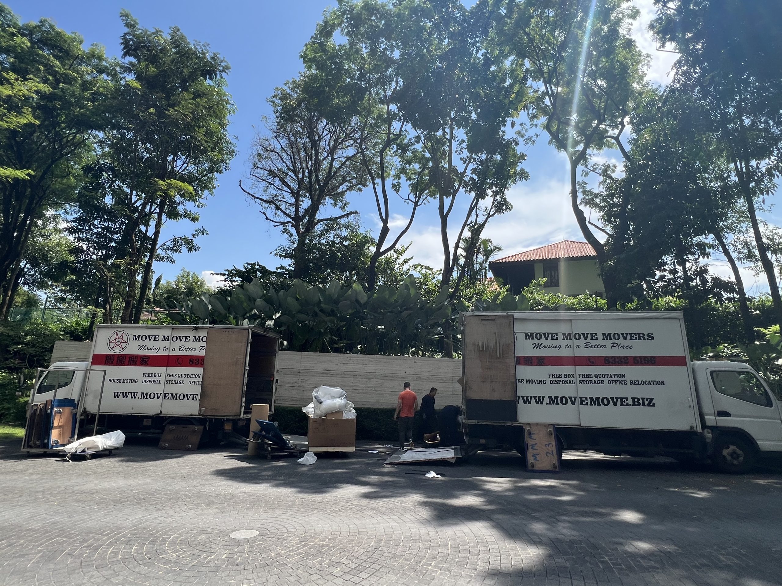 Professional movers relocating household items in a Singapore condo with protective wrapping
