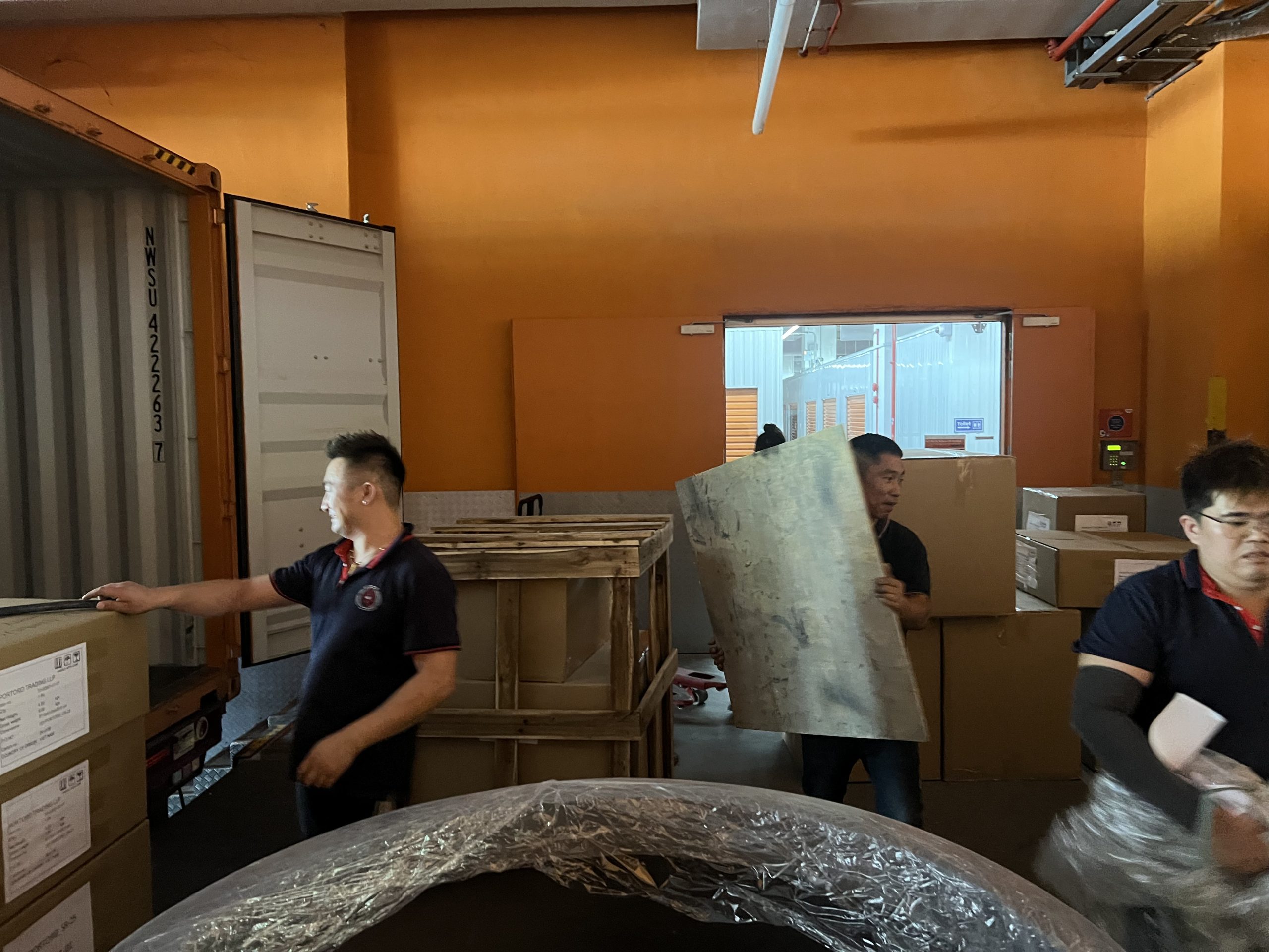 Crew carrying bulky leftover items through an indoor loading area in Singapore