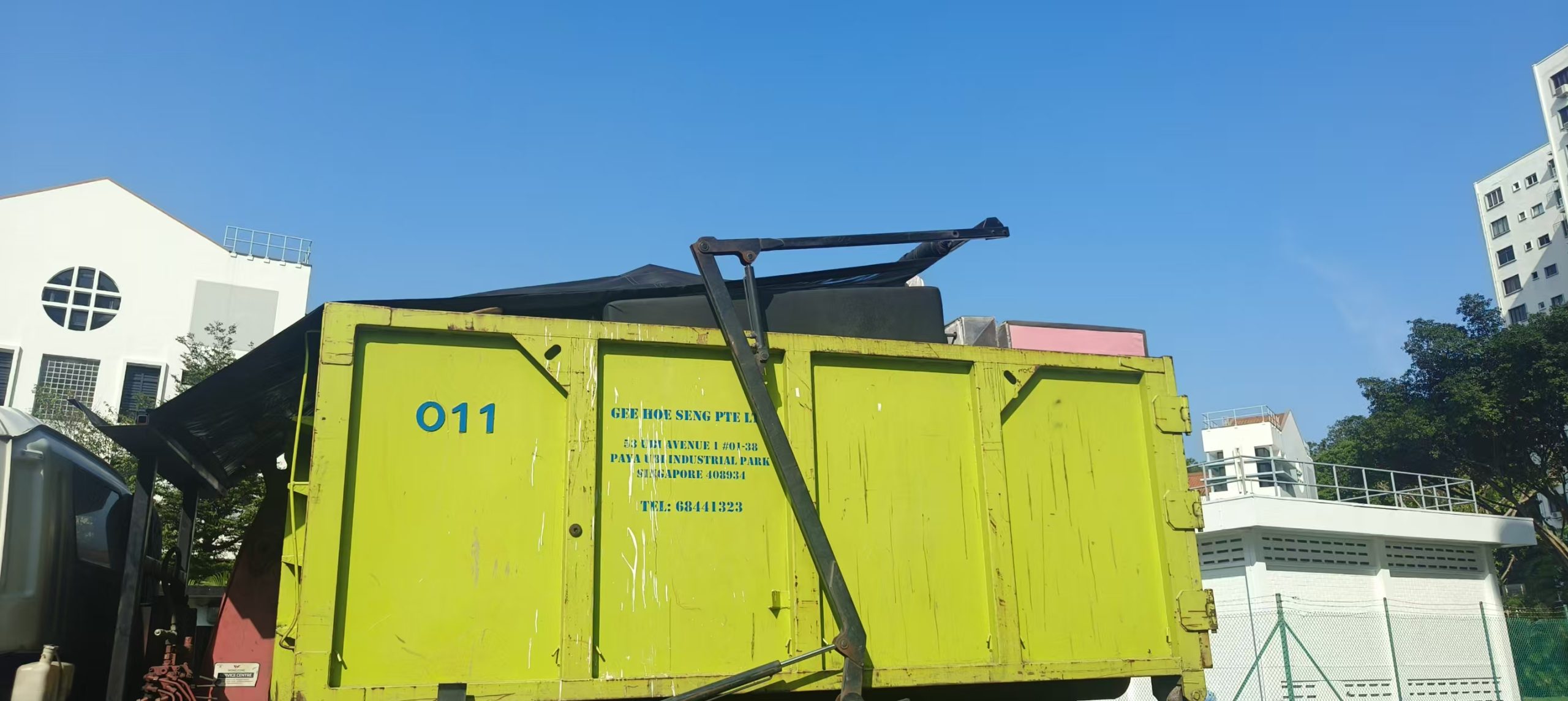 Side view of a green skip tank prepared for bulky-item disposal in Singapore