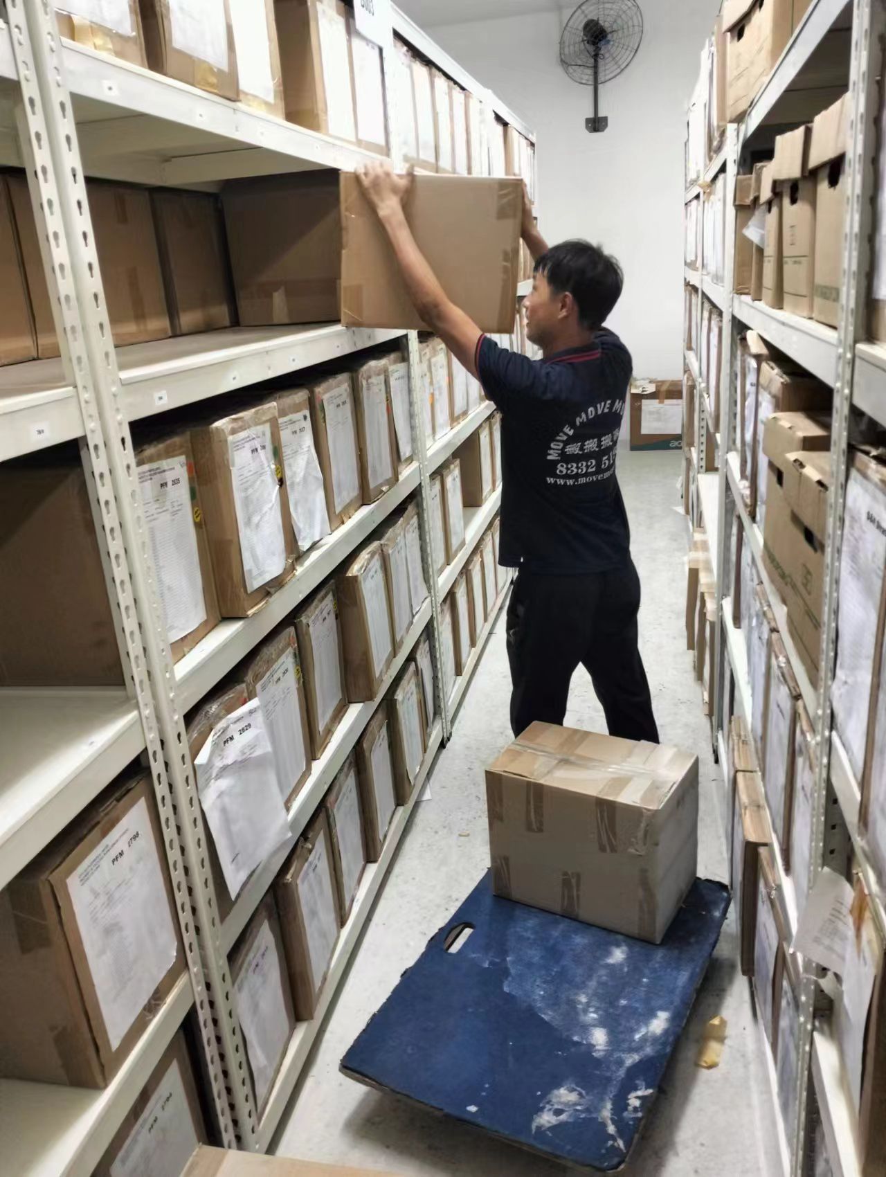 Mover lifting and loading cartons onto upper shelves in a records room