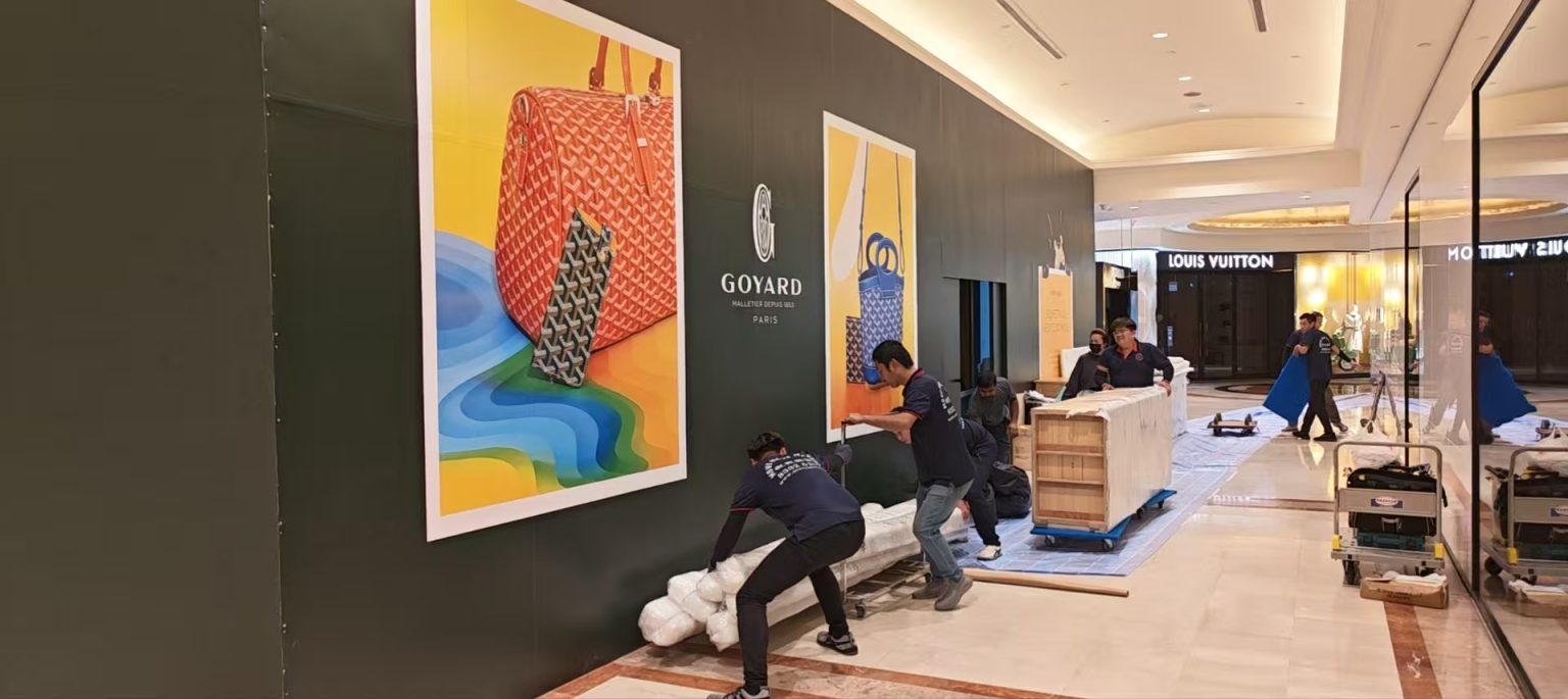 Move Move crew handling wrapped fixtures on protected flooring outside the GOYARD boutique