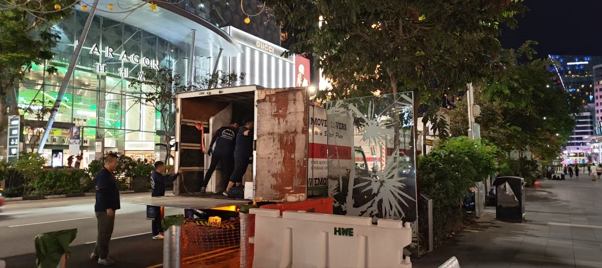 Commercial crew moving a wrapped fixture through a Singapore site during a furniture-led job