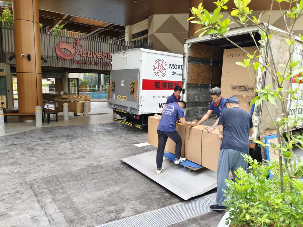 Four movers loading large boxed gym equipment onto a lorry tail lift at ActiveSG