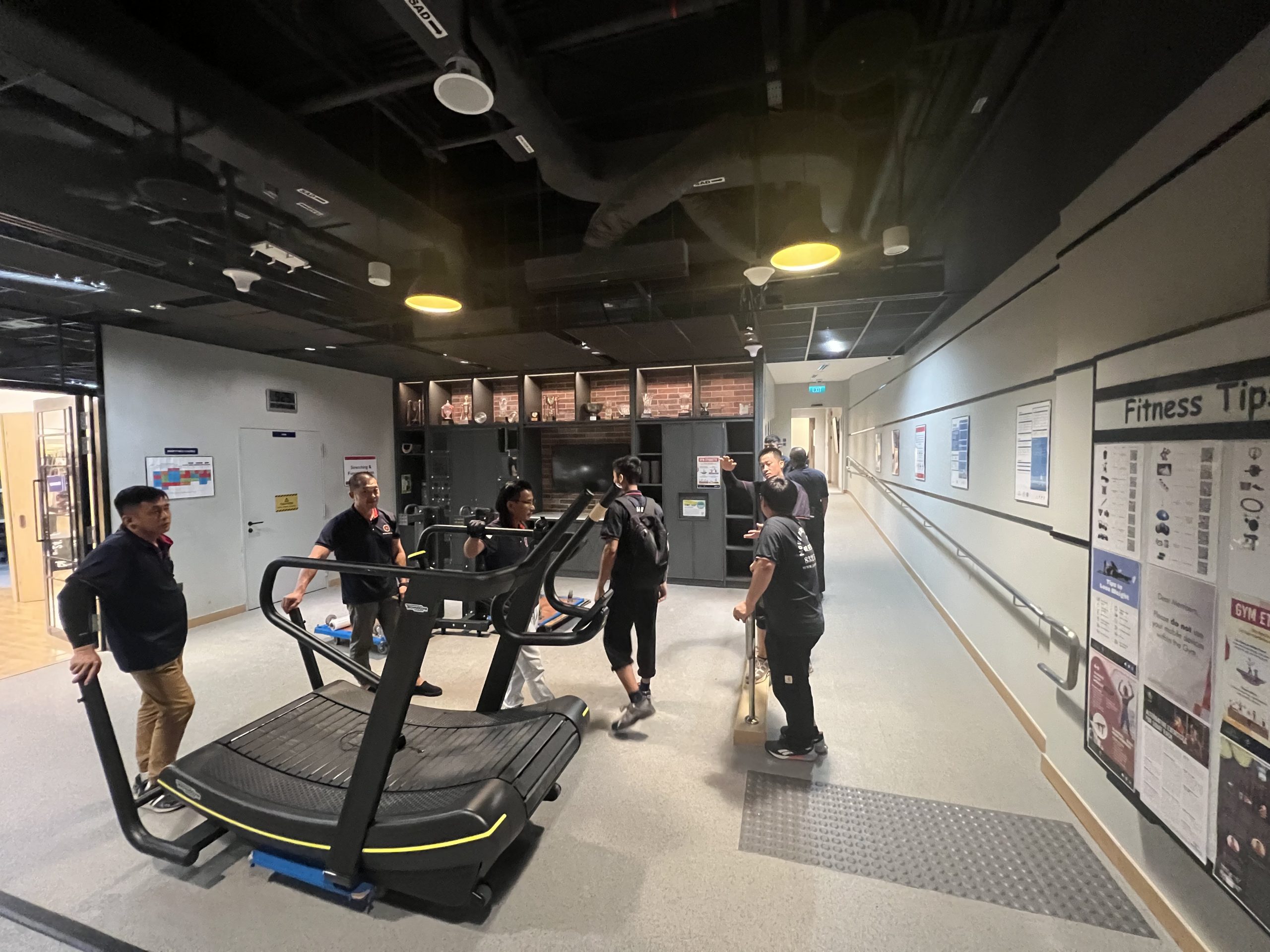 Commercial crew moving bulky office pieces through an MRT-linked concourse in Singapore