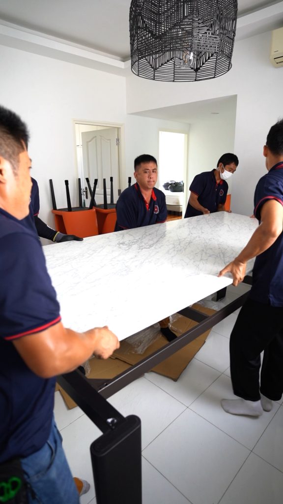 Move Move Movers team carrying a large marble tabletop inside a condominium unit