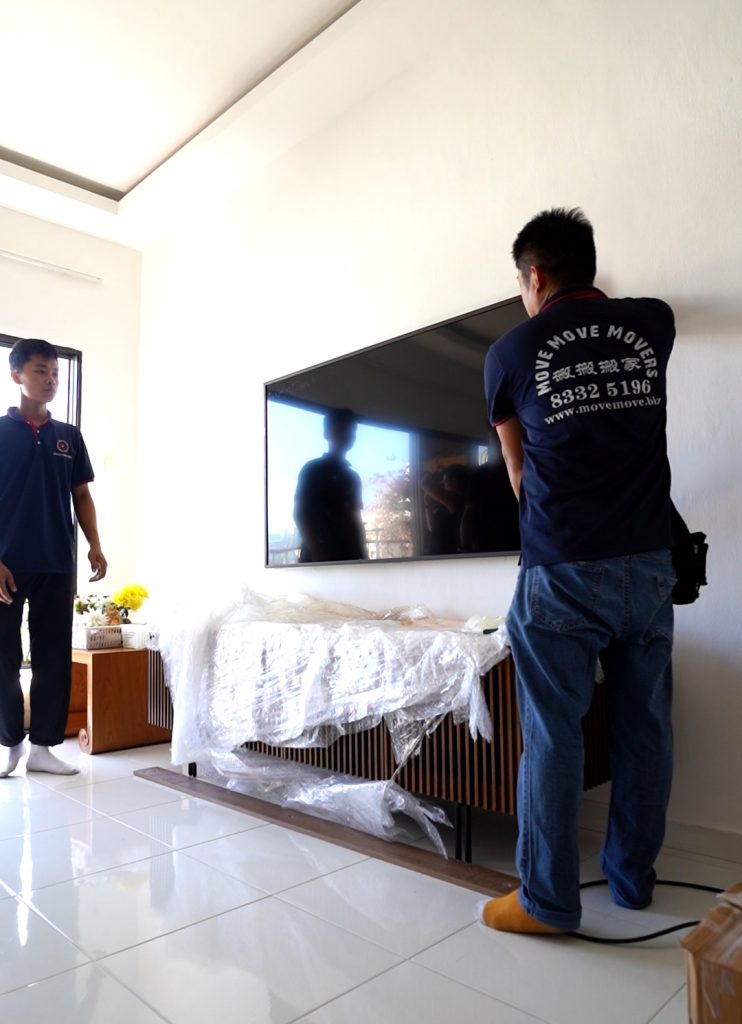 Remounting a large TV on the wall during moving day in Singapore Title