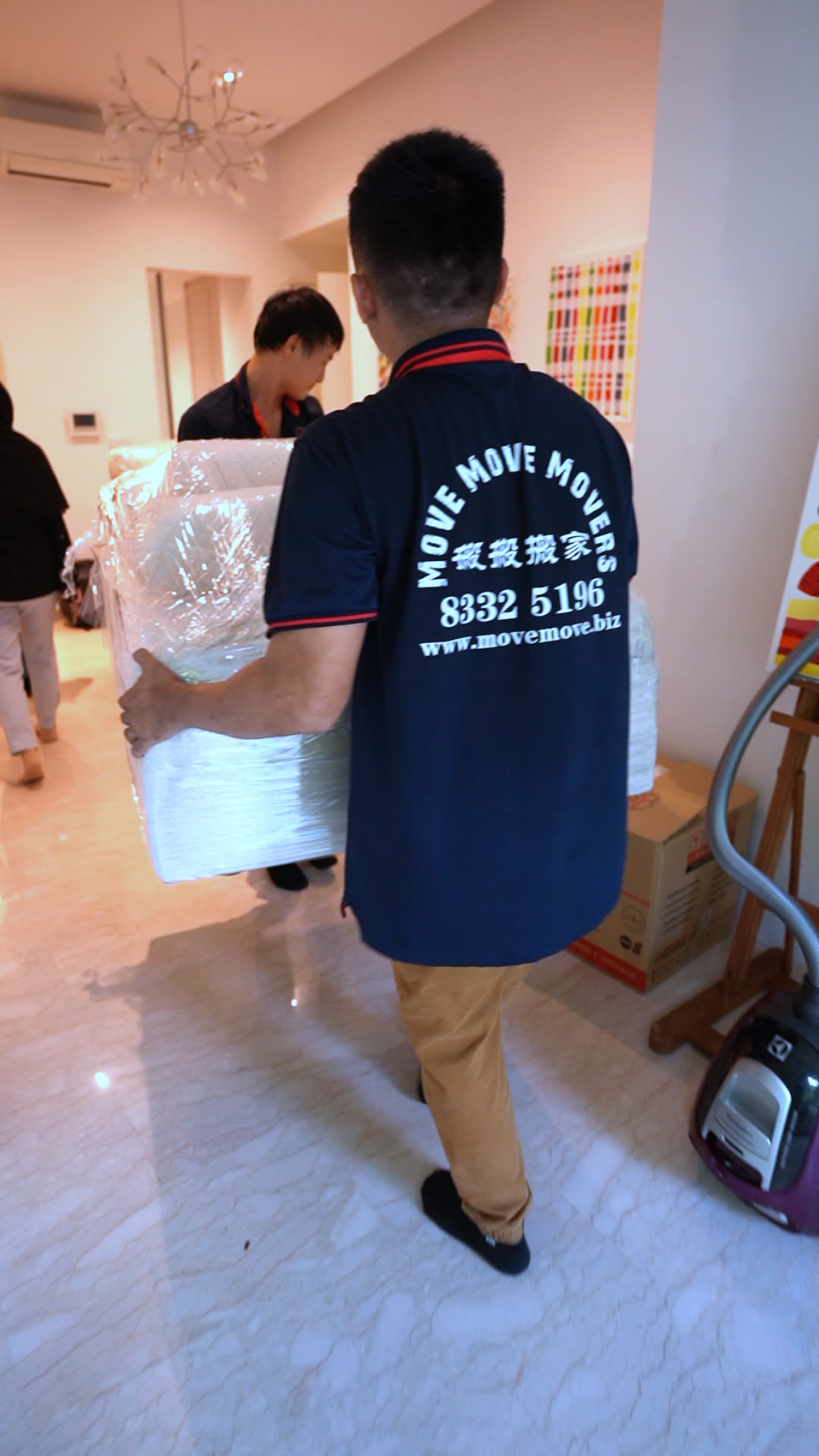 Wrapped sofa-sized item being carried through an indoor route in Singapore