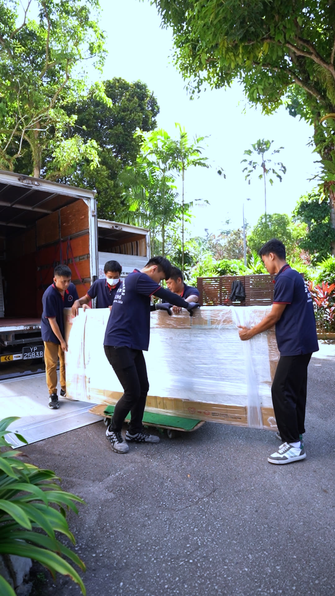 Wrapped sofa-sized furniture being carried out from a Singapore property