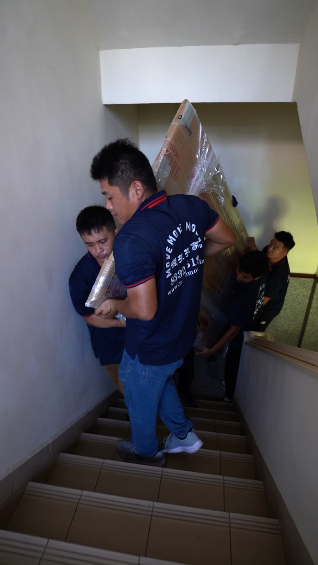 Large furniture being carried down a staircase for disposal in Singapore
