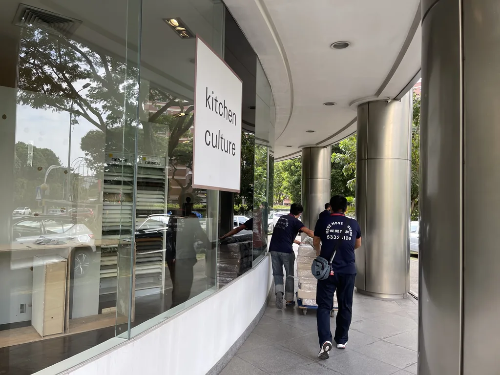 Move Move Movers crew pushing wrapped commercial items along a covered corridor