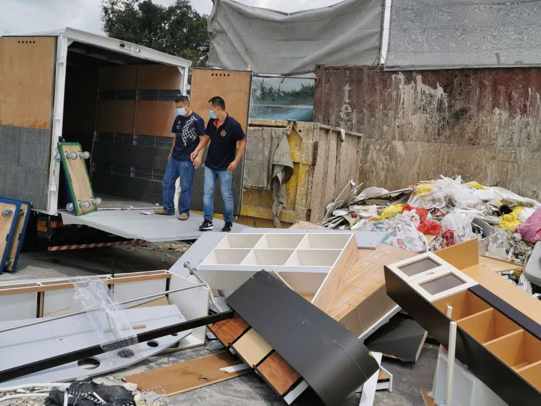 Dismantled cabinets and mixed furniture beside a Move Move Movers lorry at a disposal site
