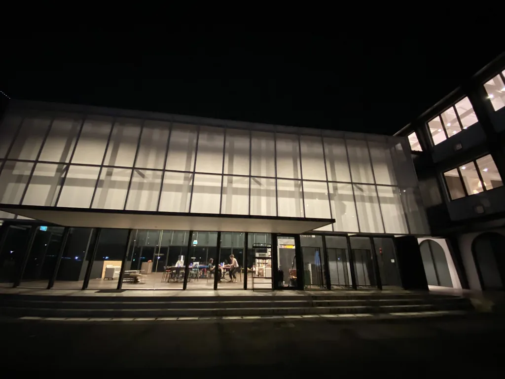 Commercial building exterior at night with interior work visible through the windows