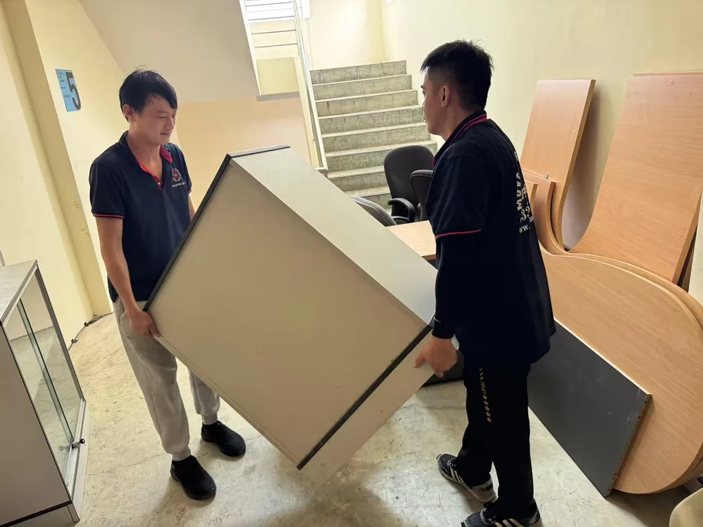 Move Move Movers crew carrying an office cabinet beside dismantled desks and chairs
