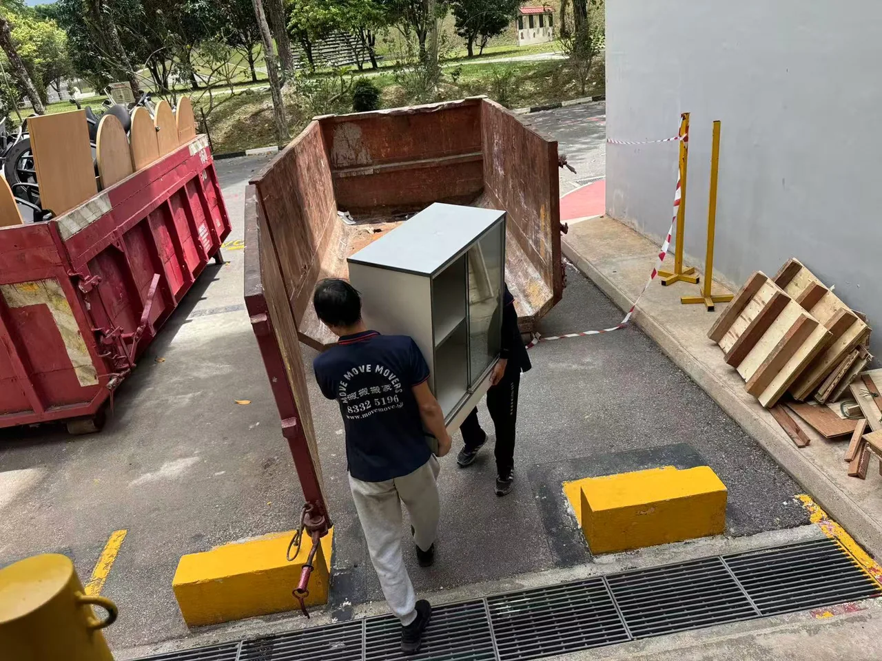 Move Move Movers crew carrying an office cabinet between skips containing desks and chairs