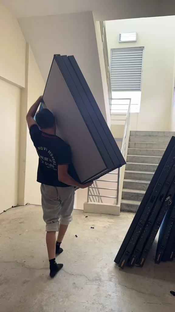 Move Move Movers crew carrying office partition panels beside a stair route
